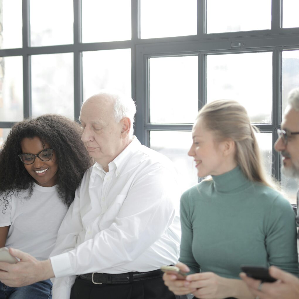 Group of colleagues looking at a smartphone together in a bright office.
