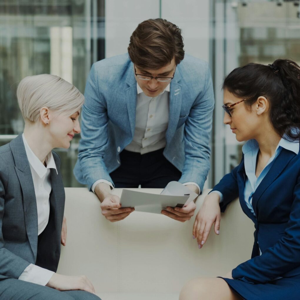 Three professionals reviewing documents together in a modern office setting.